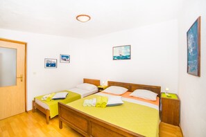 A room with two single beds, a wooden wardrobe, and a door.