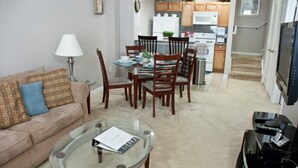 A living room with a glass coffee table, a sofa, and a dining area with wooden chairs and a table. - Venetian Bay Townhome 3 Bedroom Townhouse by RedAwning (Kissimmee)