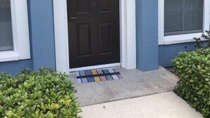 A house with a dark brown front door, white trim, and a small welcome mat. - Venetian Bay Townhome 3 Bedroom Townhouse by RedAwning (Kissimmee)