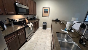 A kitchen with wooden cabinets, a stainless steel sink, a microwave, and a coffee maker. - Paradise Palms-4 Bedroom Townhome-3001PP 4 Townhouse by RedAwning (Kissimmee)