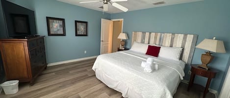 Ein Schlafzimmer mit Bett, Deckenventilator, Kommode und Fernseher.
