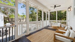 A covered porch with white railings, outdoor furniture, and a ceiling fan. - Charming home perfectly located near Seaside, Watercolor, and the best of 30A (Seagrove Beach)