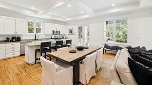 A spacious kitchen with white cabinetry, a wooden dining table, and a black and white sofa. - Charming home perfectly located near Seaside, Watercolor, and the best of 30A (Seagrove Beach)