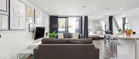A modern living room with a grey sofa, a flat-screen TV, and artwork on the walls.