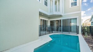 Una casa de dos pisos con piscina, puertas correderas amplias de vidrio y un balcón.