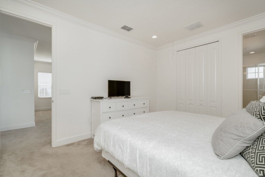A bedroom with a large bed, a dresser, a television on the dresser, and a closet with sliding doors.