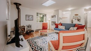 Una sala de estar con chimenea, un sofá, un sillón y un alfombra estampada.