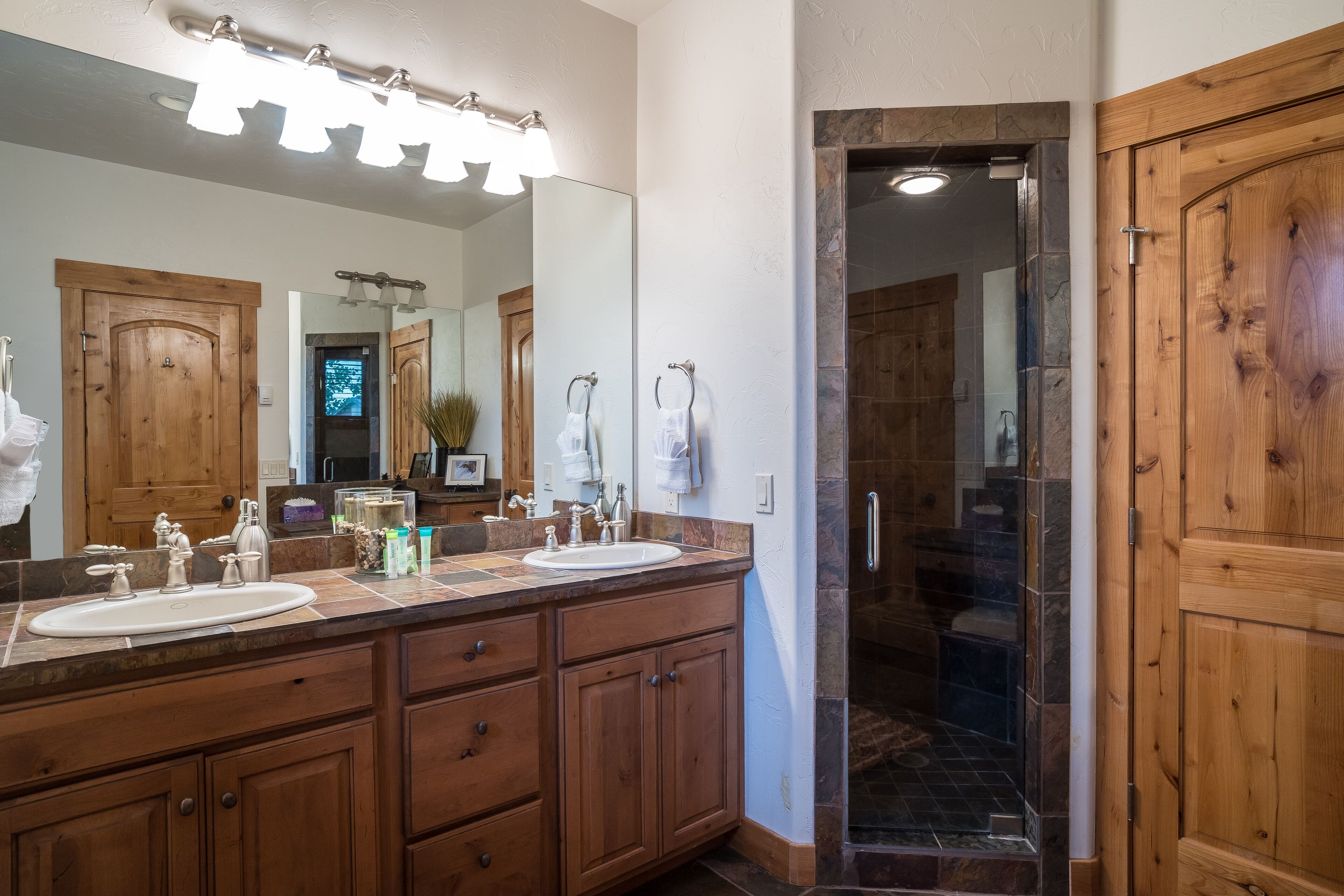 A bathroom with wooden cabinets, a double sink, and a large mirror.