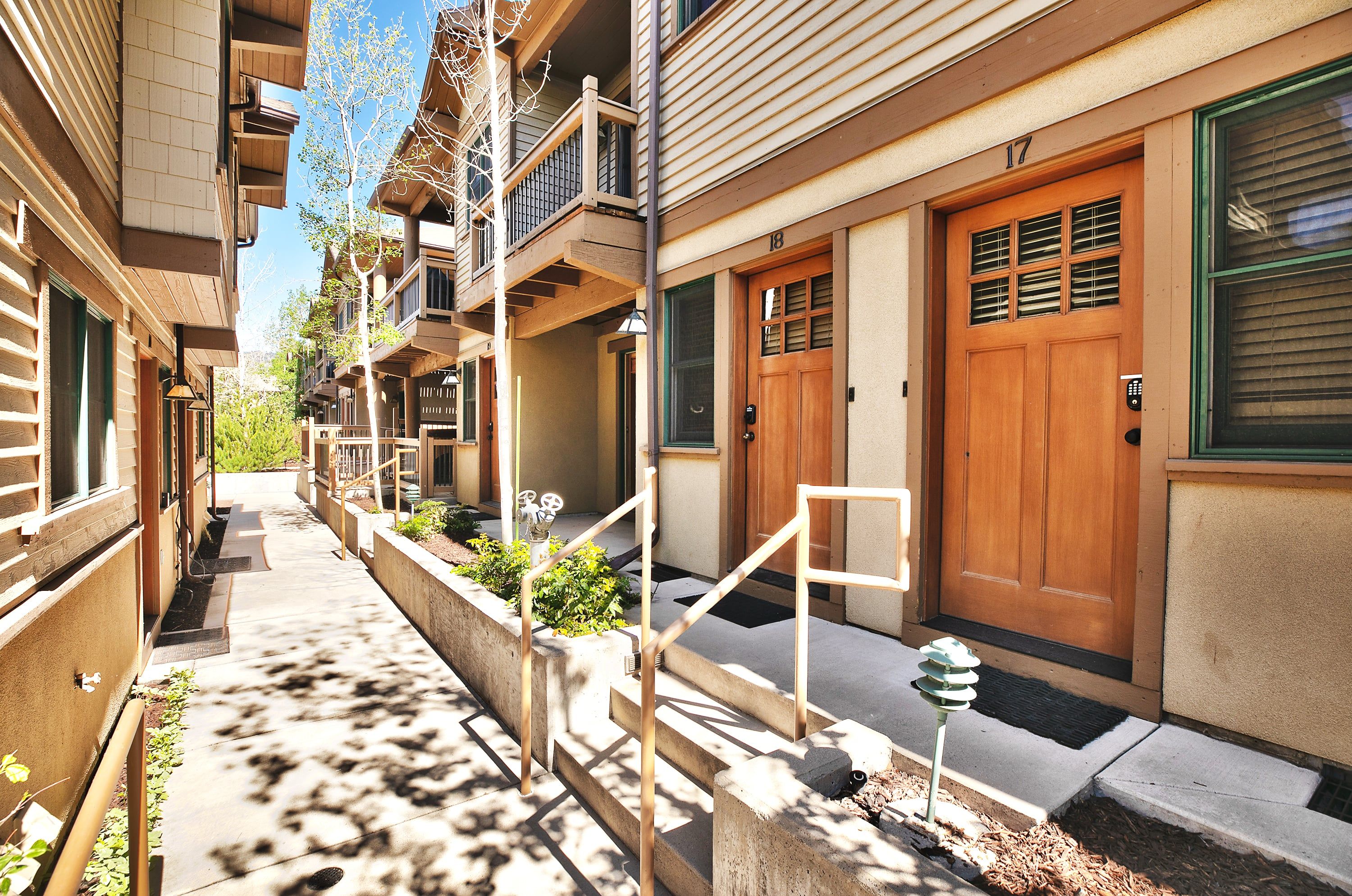 Une ruelle étroite entre deux bâtiments, avec des balcons en bois, une porte en bois et un petit jardin.