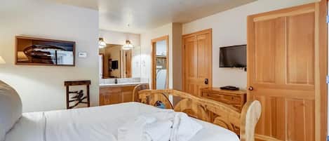 Una habitación de hotel con una cama, un armario de madera, un televisor y un espejo.