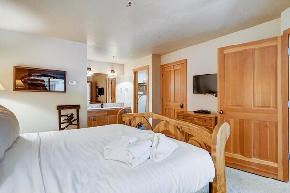 Una habitación de hotel con una cama, un armario de madera, un televisor y un espejo.