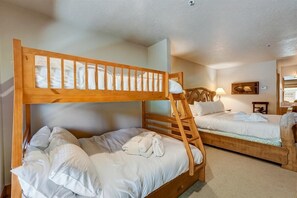 Una habitación con dos literas, una mesita de noche con lámpara y un cuadro en la pared.