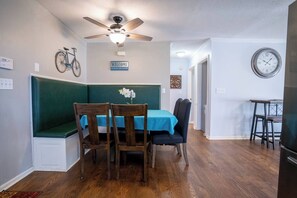 A dining area with a table set for two, a bench, and a ceiling fan. - Lakefront Home: Game Room & Dock (Eatonton)