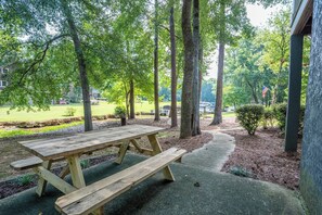 A picnic table in a park with trees and a grassy area in the background. - Lakefront Home: Game Room & Dock (Eatonton)