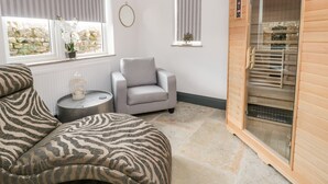 A room with a sofa, a chair, a small table with a decorative item, and a sauna. - 6 Lock View (Skipton)