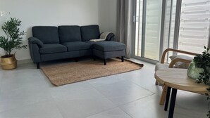 A modern living room with a grey sectional sofa, a wooden dining table, and a potted plant.
