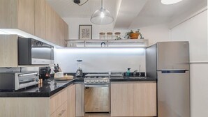 Une cuisine moderne avec des meubles en bois, un réfrigérateur en acier inoxydable, un four encastré et un four à micro-ondes.