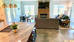 Una cocina amplia con una isla grande, comedor y un espacio de sala acogedor con chimenea.