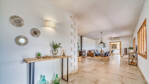 A spacious living area with a fireplace, a dining table, and a kitchen in the background. - Finca with panoramic views Es Claperas in Mallorca (Inca)