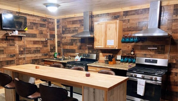 A kitchen with wooden walls, a central island, a stove, and a sink.