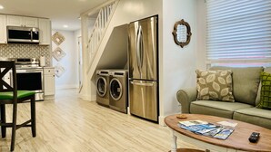 Un espace de vie compact comprenant un coin cuisine, un coin repas et un espace détente avec un canapé et une table basse.