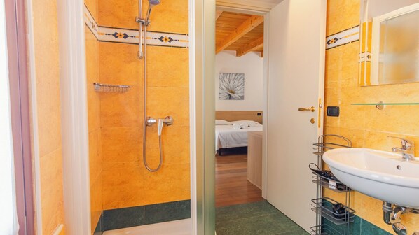 A bathroom with a shower, sink, and a bed visible through an open door. - Antiche Mura 2 - One Bedroom Guest House, Sleeps 2 (Verona)