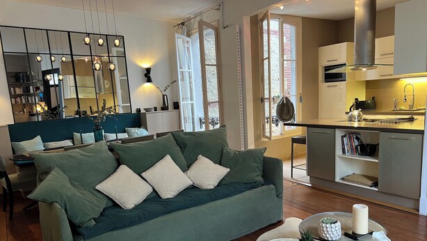 Un salon moderne avec un canapé vert, un tapis blanc et une petite table ronde décorée de bougies.