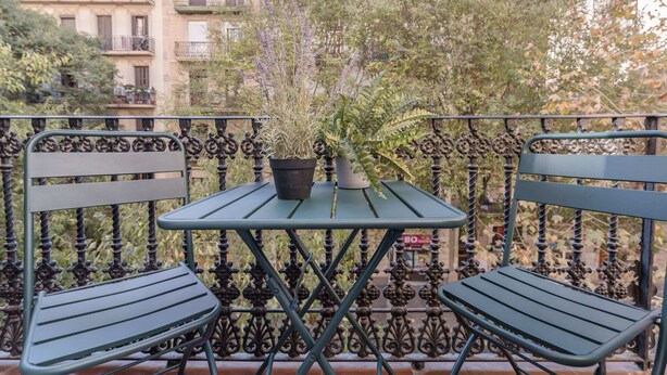 A balcony with a table and two chairs, surrounded by ornate metal railings. - Sweett | Rocafort 102 (Barcelona)