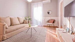 A living room with a sofa, a coffee table, a chair, a TV, and a patterned rug. - Sweett | Rocafort 102 (Barcelona)