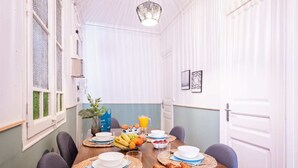 A breakfast setting with a wooden table, plates, bowls, croissants, and a fruit basket. - Sweett | Rocafort 203 (Barcelona)