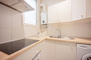 A compact kitchen with a built-in stove, a sink, and a dishwasher. - Sweett | Rocafort Principal 3 (Barcelona)