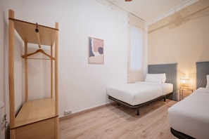 A hotel room with a bed, a bedside table, a hanging wardrobe, and a wall-mounted artwork.
