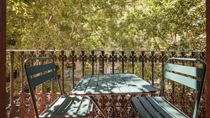 A balcony with a table and two chairs, surrounded by a wrought iron railing. - Sweett | Rocafort Principal 3 (Barcelona)
