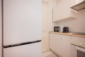 A compact kitchen with a refrigerator, microwave, toaster, and oven.