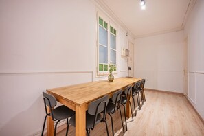 A room with a wooden table and six chairs, a window with frosted glass, and a vase with flowers on the table. - Sweett | Rocafort Principal 3 (Barcelona)