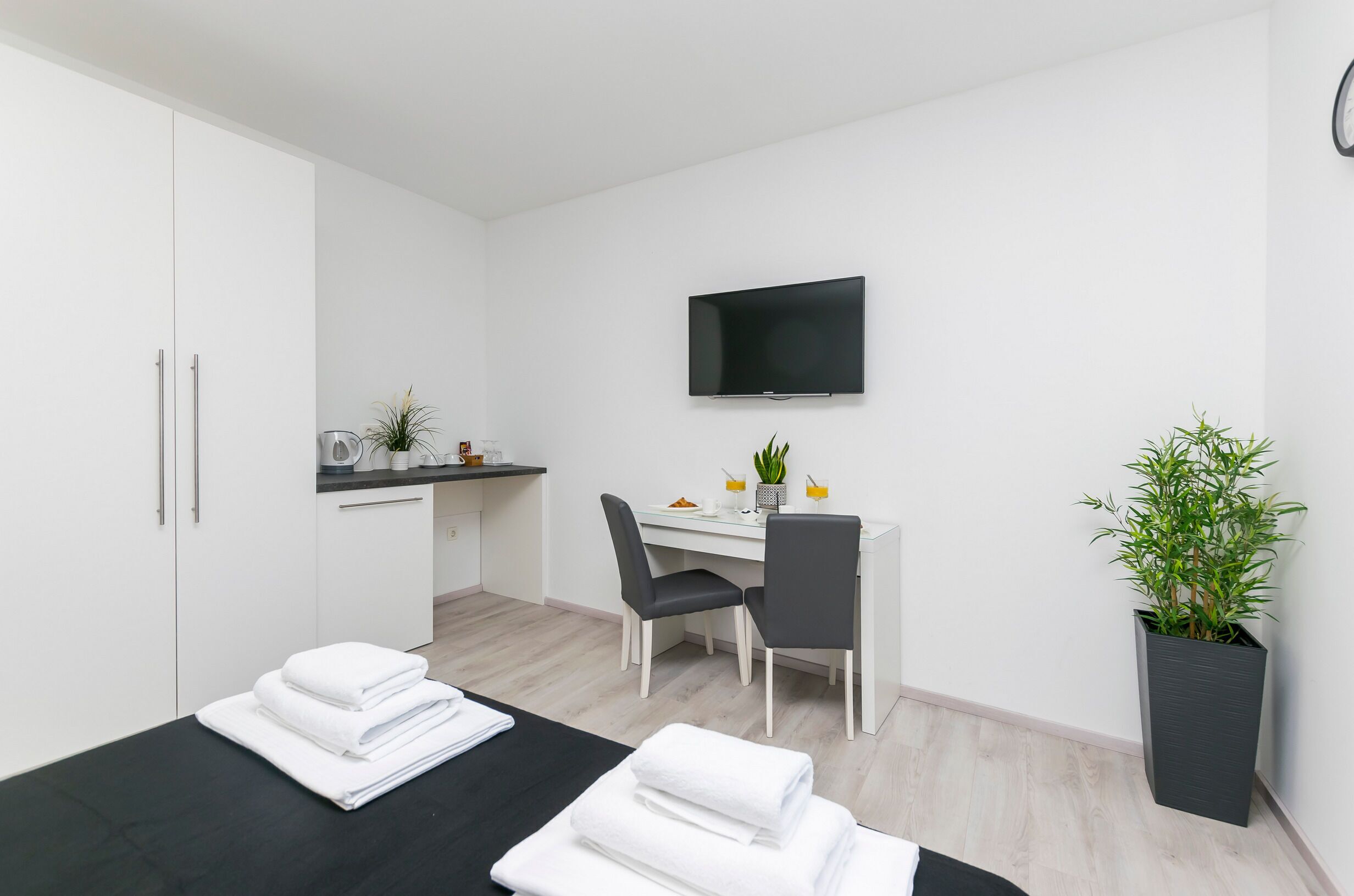 Una habitación de hotel moderna con una cama, un escritorio con una silla, un televisor de pantalla plana y una planta en maceta.