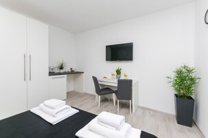 Una habitación de hotel moderna con una cama, un escritorio con una silla, un televisor de pantalla plana y una planta en maceta.