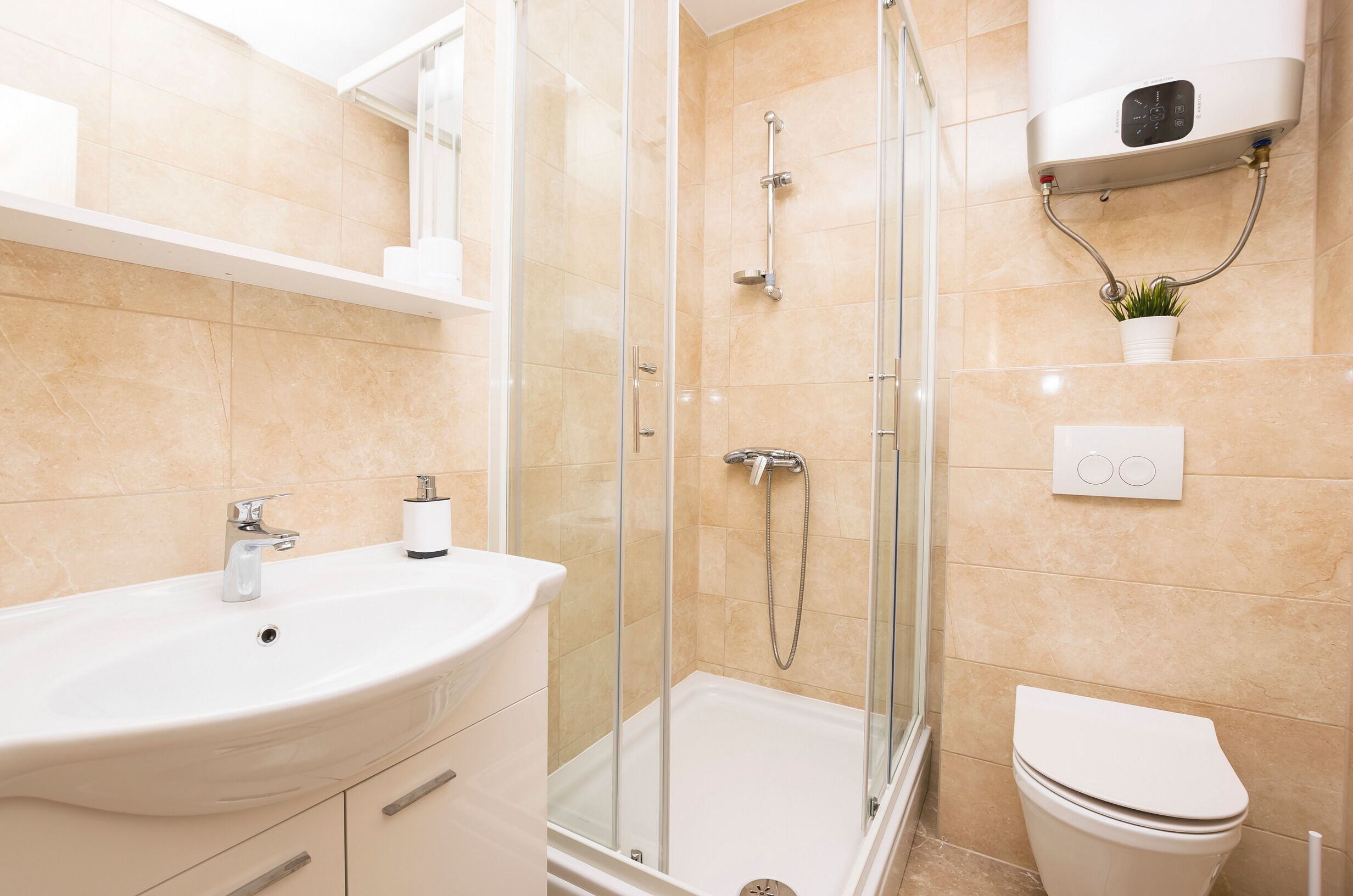 A modern bathroom with a glass-enclosed shower, a white sink, and a toilet.
