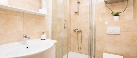 A modern bathroom with a glass-enclosed shower, a white sink, and a toilet.