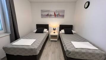 A twin room with two beds, a nightstand, a lamp, and a painting on the wall.