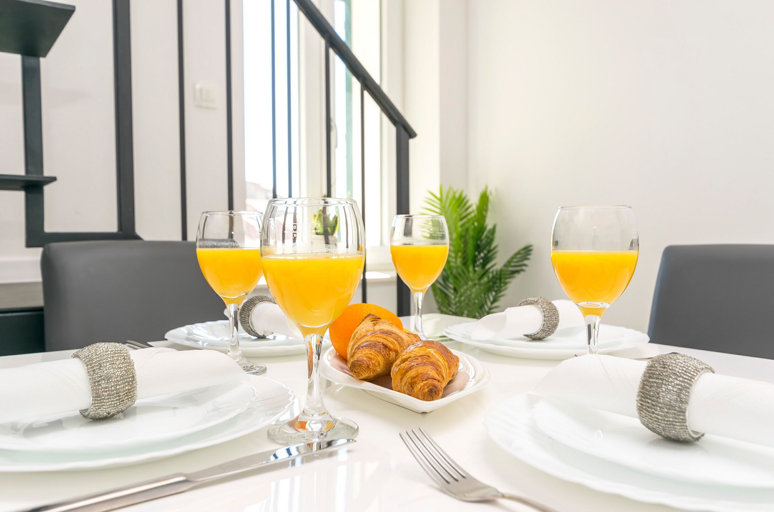 A breakfast setting with croissants, orange juice, and a plate of fruit.