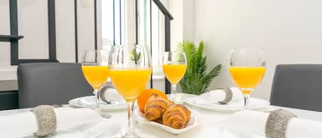 A breakfast setting with croissants, orange juice, and a plate of fruit.