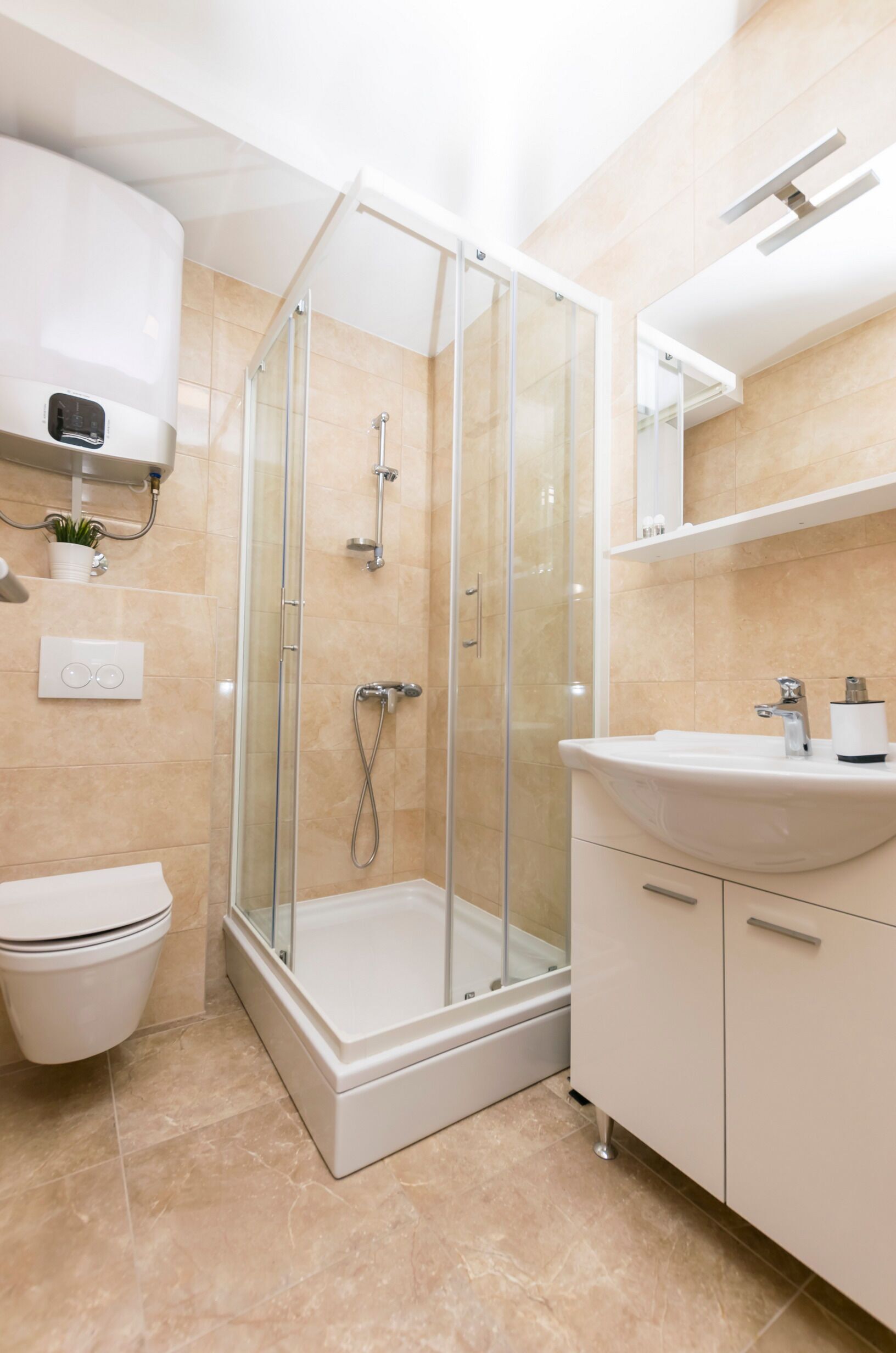 A modern bathroom with a glass-enclosed shower, a white toilet, and a sink with a mirror above it.