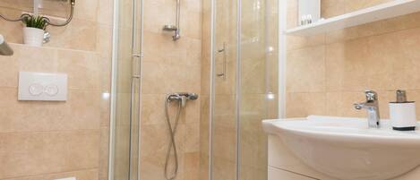 A modern bathroom with a glass-enclosed shower, a white toilet, and a sink with a mirror above it.