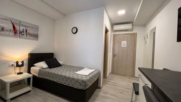 A bedroom with a bed, bedside table, lamp, and a small desk area.
