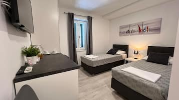 Una habitación de hotel moderna con dos camas, un escritorio, un televisor y una ventana con cortinas.