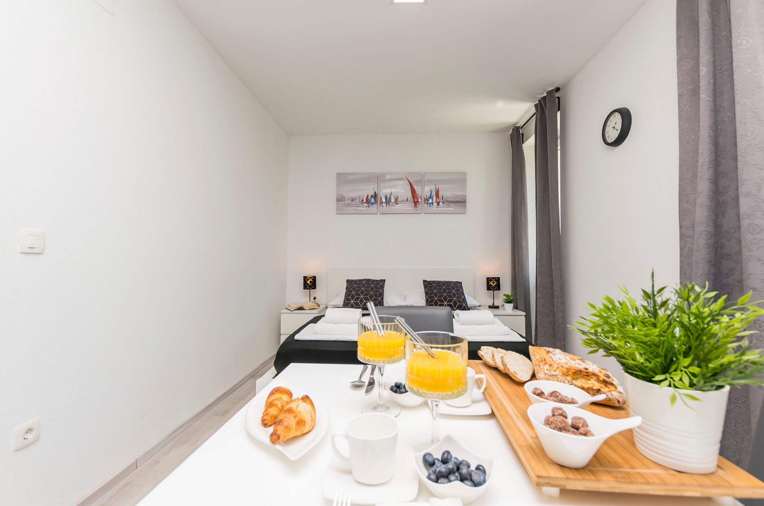 Habitación de hotel con desayunos que incluyen croissants, jugo y una planta.