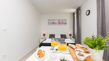 Habitación de hotel con desayunos que incluyen croissants, jugo y una planta.