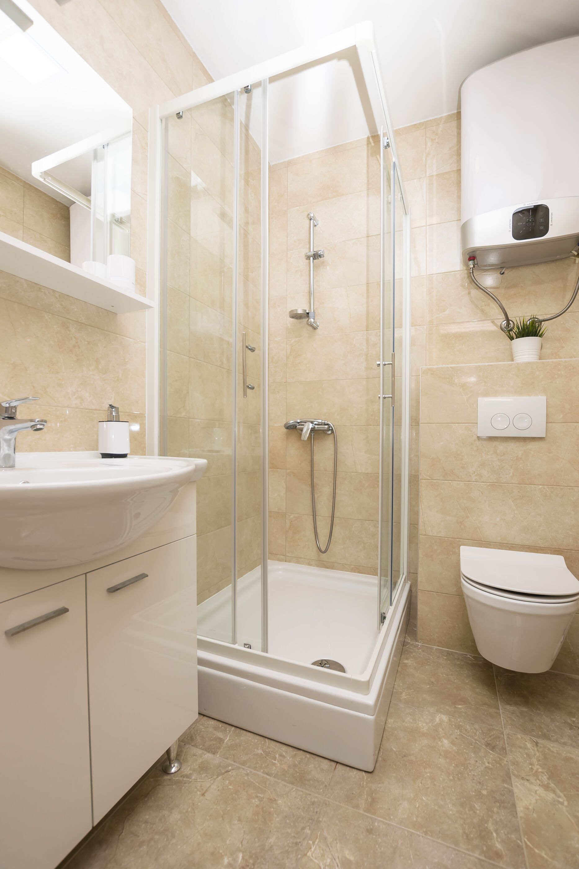 A modern bathroom with a glass-enclosed shower, a white sink, and a toilet.