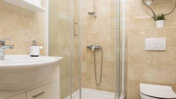 A modern bathroom with a glass-enclosed shower, a white sink, and a toilet.